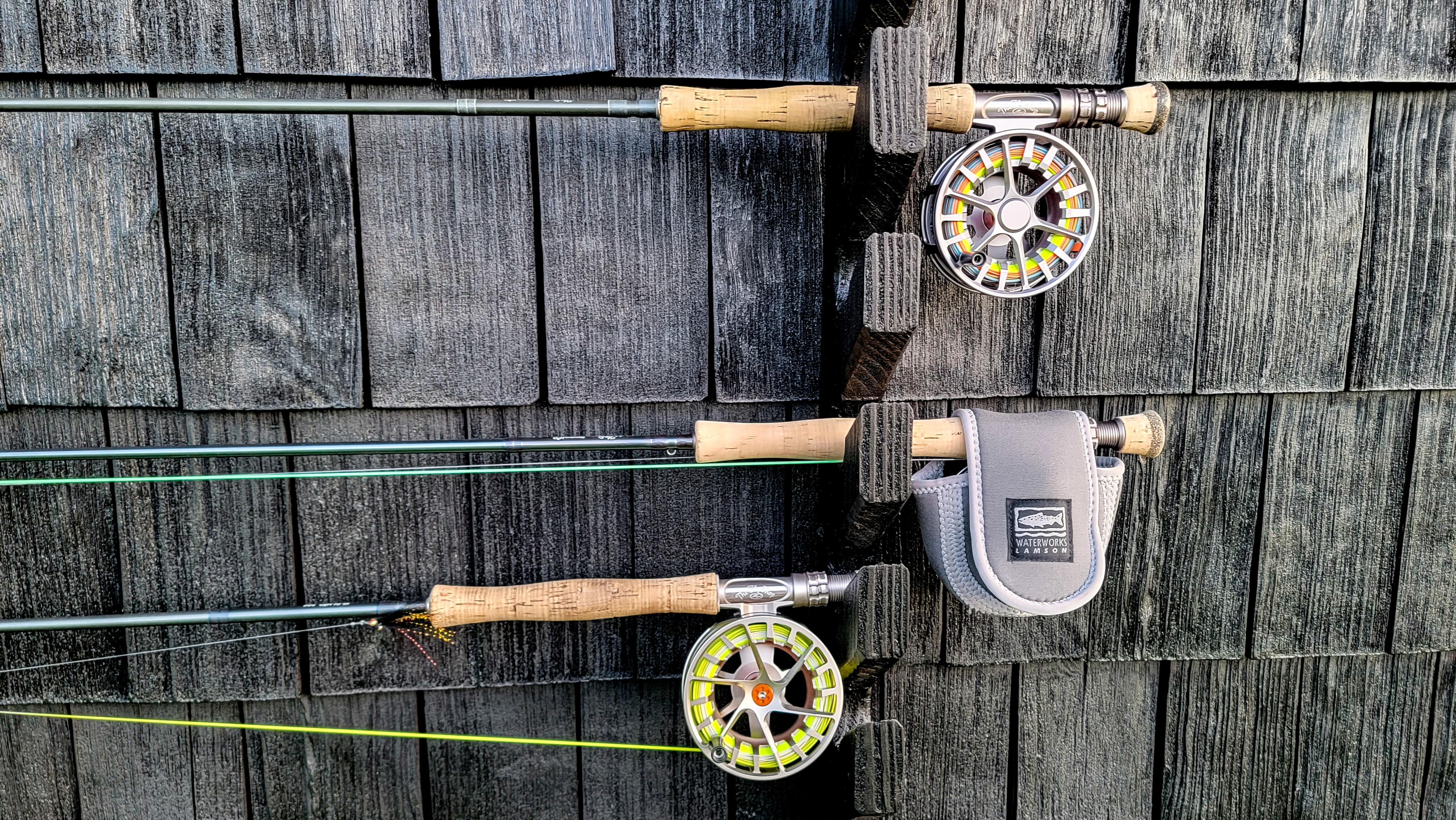 Fly rods and reels resting on weathered barn wood siding at the ranch cabin