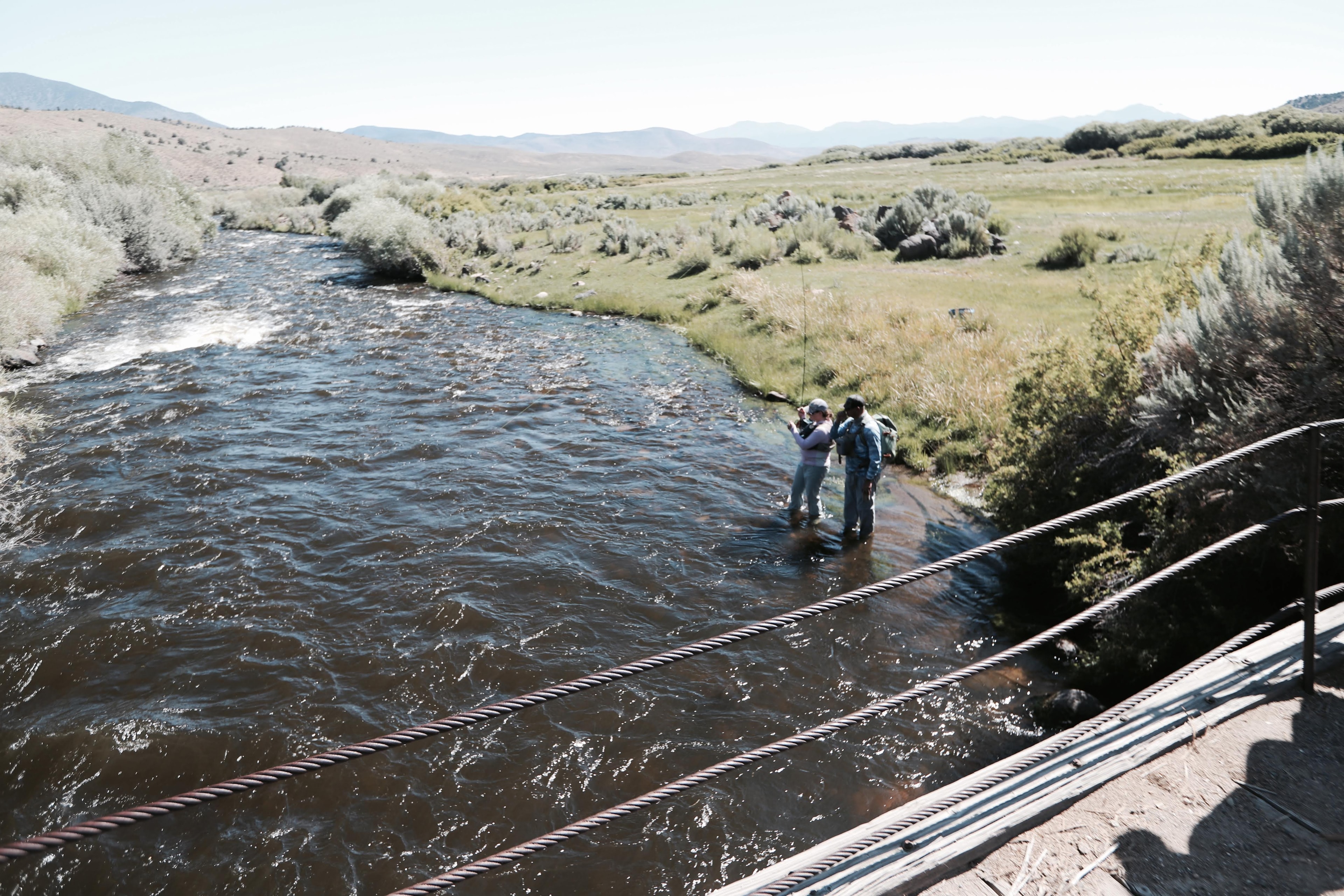Two anglers fly fishing a mountain river valley