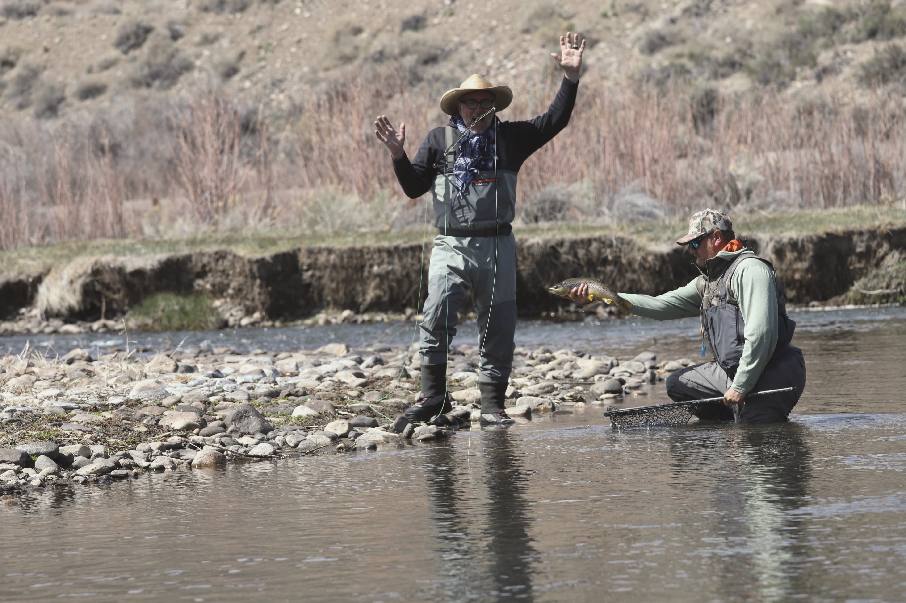 Two anglers celebrating a catch on the East Walker River, rods bent, big smiles